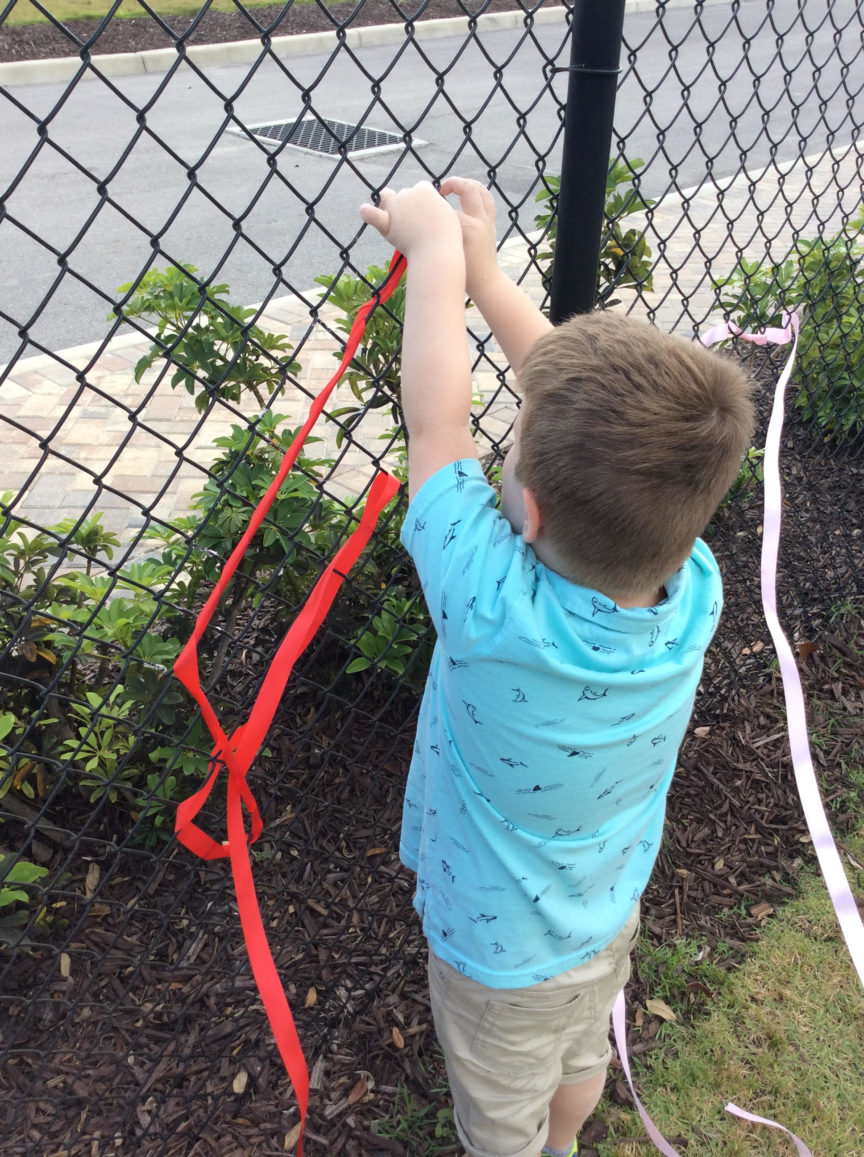Child Tying Ribbons On Fence